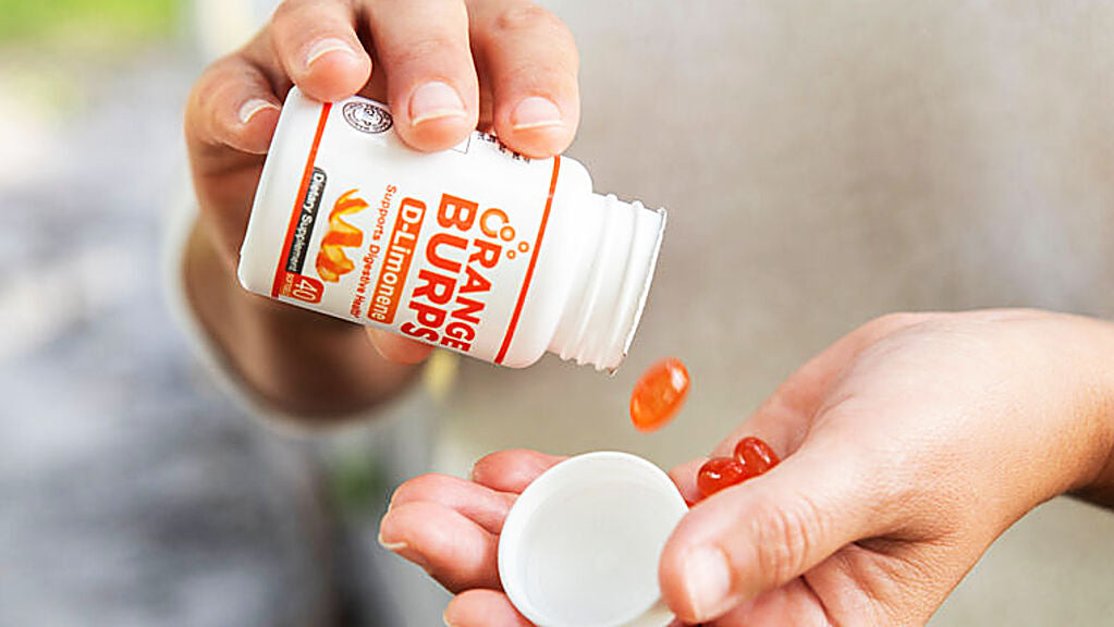 Person pouring Orange Burps D-Limonene softgels from bottle